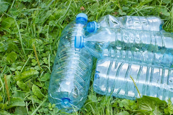 Plastic bottles of mineral water on grass in park, littering of environment