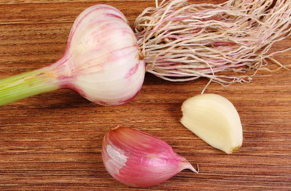 Whole garlic with roots and cloves on wooden table