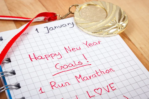 New years resolutions written in notebook and gold medal