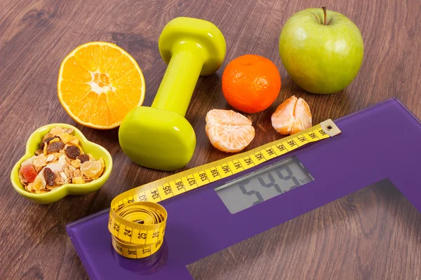 Digital scale with tape measure, dumbbells, fruits, muesli, slimming concept