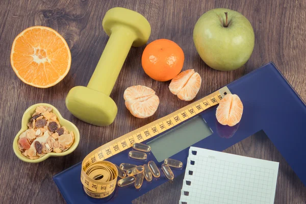 Digital scale with tape measure, tablets, dumbbells, fruits, muesli, slimming concept