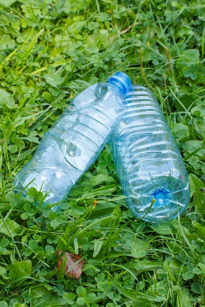 Plastic bottles of mineral water on grass in park, littering of environment