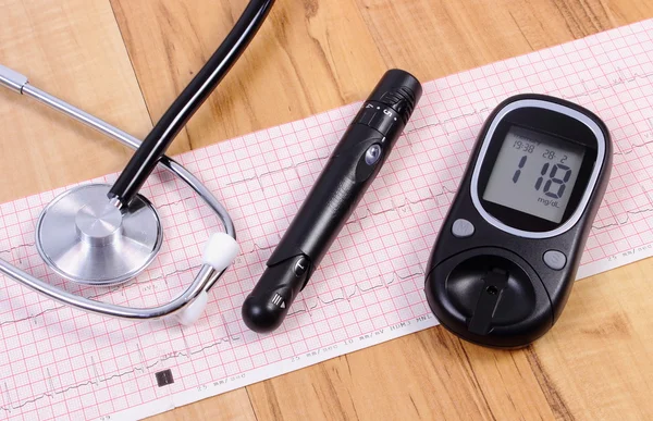 Glucometer with lancet device and stethoscope on electrocardiogram graph