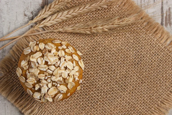 Fresh muffins with oatmeal and ears of rye grain, delicious healthy dessert, copy space for text on jute canvas