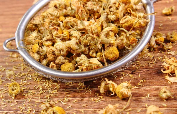 Dried chamomile on metal sieve, alternative medicine