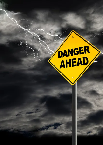 Danger Ahead Sign Against Cloudy and Thunderous Sky