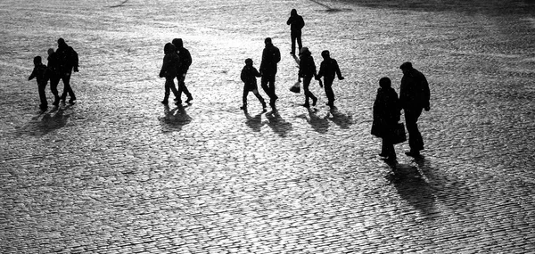 Group of people walking along the pavement day black white