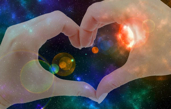 Hands in form of heart on the background of the cosmos