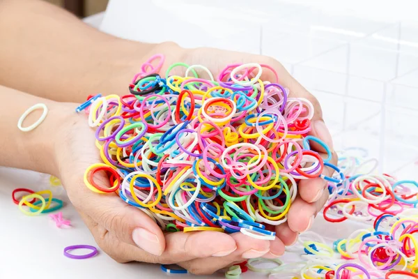 Hands and pile of small round colorful rubber bands rainbow colo