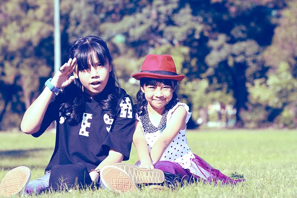 Two young girl sitting on grass in cross proccess tone