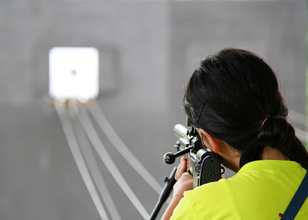 Rear view of girl  shooting target with gun