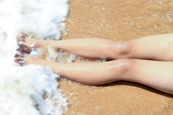 Water  splash on nice female legs on beach