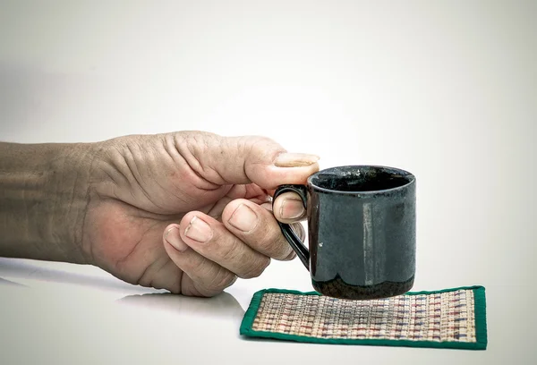Old Man hand hold with black cup on the white table