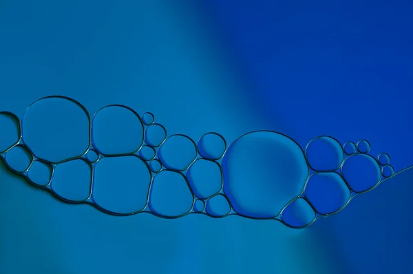 Blue drops of oil and air bubbles on the water