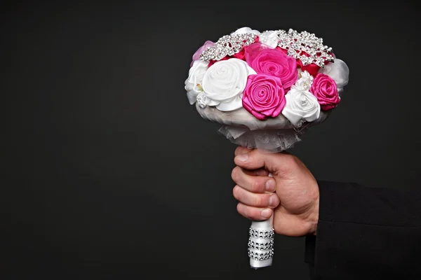 Hand holds wedding bouquet for bride