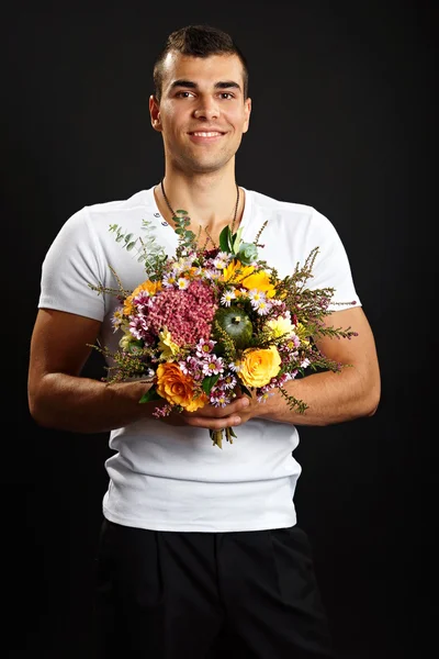 Smiling man holds bouquet of flowers