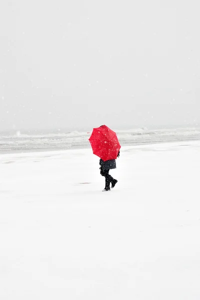 Person on the beach with red umbrella