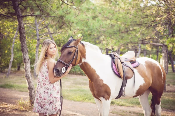 Beautiful young lady wearing vintage dress riding a horse at sun