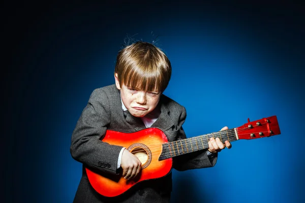 Red-haired preschooler boy with ukalele, music concept