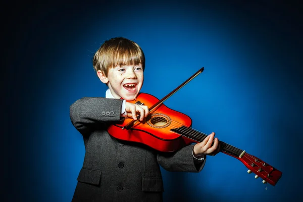 Red-haired preschooler boy with ukalele, music concept