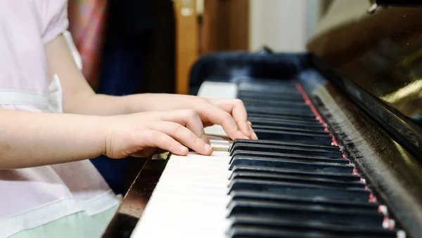 Girl's hands and piano keyboard close-up view