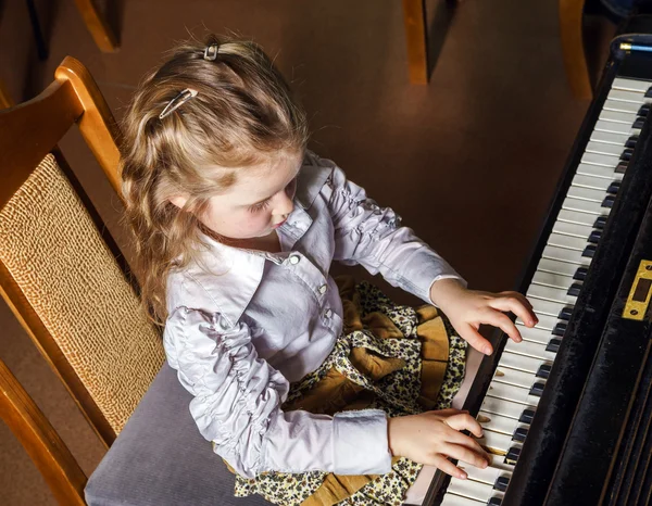 Cute little girl playing grand piano in music school