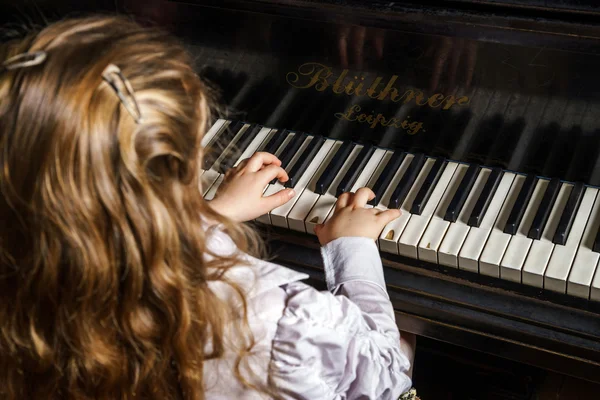 Cute little girl playing grand piano in music school