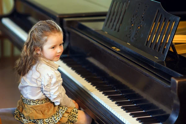 Cute little girl playing grand piano in music school