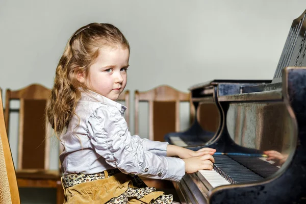 Cute little girl playing grand piano in music school