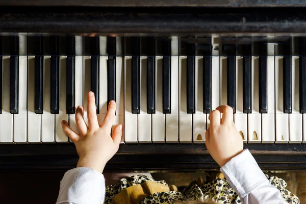 Cute little girl playing grand piano in music school