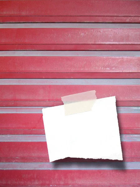 Single ripped piece of paper on red metal shutter