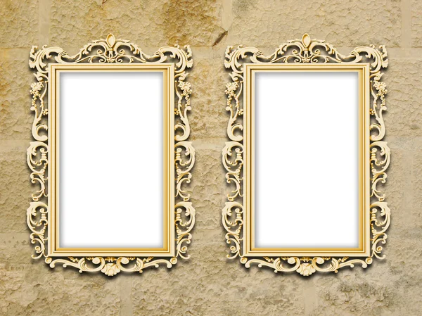 Two golden baroque frames on grungy yellow concrete wall