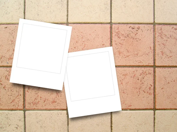 Two blank square instant photo frames on square clay tiles