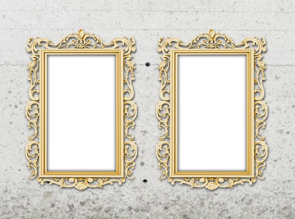 Two golden baroque frames on grey concrete wall