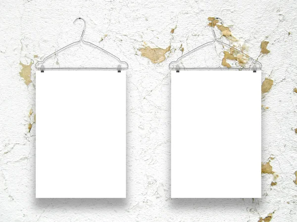 Two vertical sheets with clothes hangers on weathered ochre and white wall