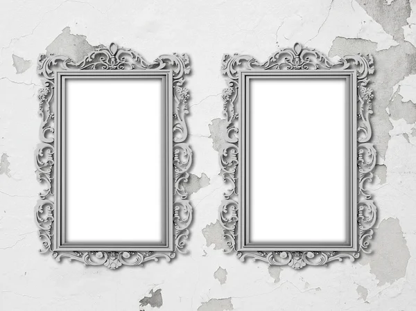 Two silver baroque frames on grey scratched and cracked concrete wall