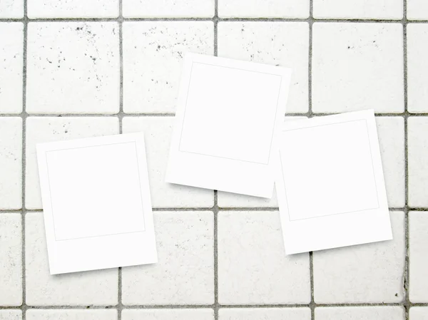 Three square blank instant photo frames on grey tiles pavement