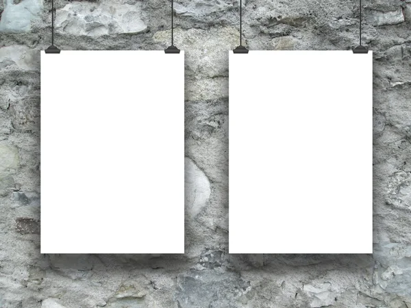 Two hanged paper sheets with clips on grey stone wall