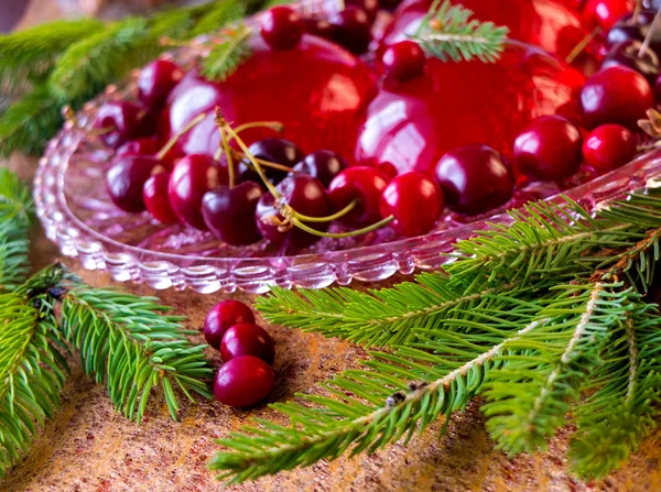 Christmas dessert - red berries jelly with cherries and christmas twig