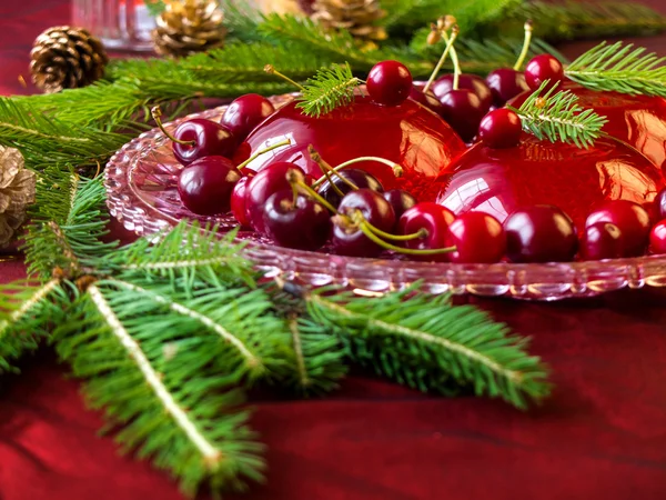 Christmas dessert - red berries jelly with cherries and christmas twig
