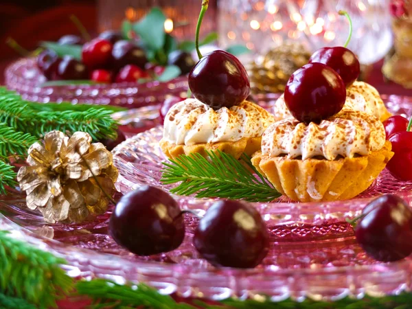 Christmas dessert - cupcakes with red berries cherries, cranberries and christmas tweeg