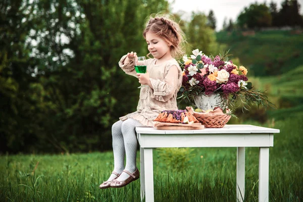 Little baby girl eats chocolate cake in nature at a picnic