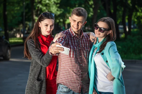 Two young women and the guy taking selfie with mobile phone