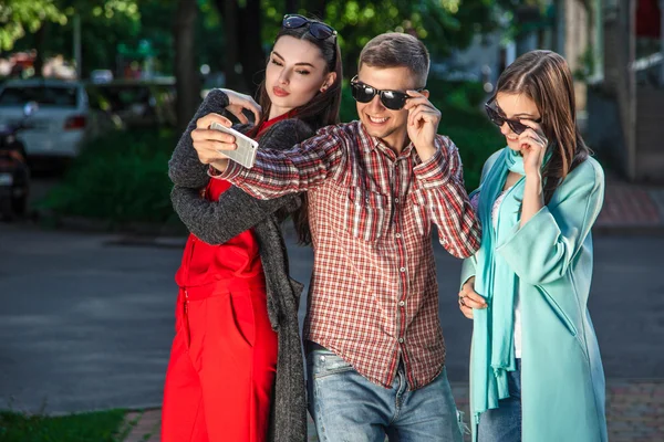 Two young women and the guy taking selfie with mobile phone