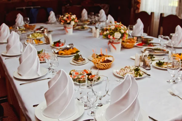 Elegant beautiful decorated table with meals and tableware at wedding reception closeup