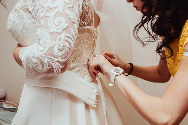 Beautiful bridesmaid tying bow on wedding dress