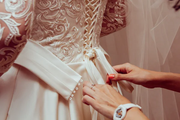 Beautiful bridesmaid tying bow on wedding dress
