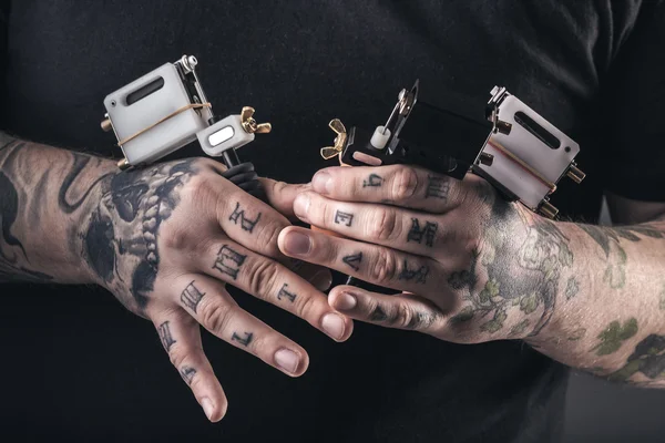 Man tattoo artist with tattoo machines