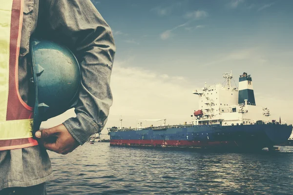 Harbor dock worker talking on radio with ship background