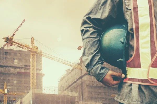 Construction worker checking location site with crane on the background